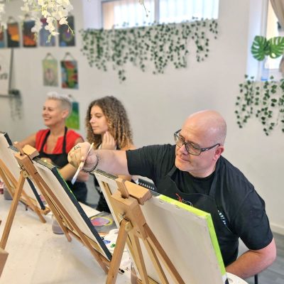 Fiesta familiar en una sesión de pintura con cata de vinos pintando cuadros en pintura acrílica.