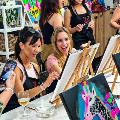 Chicas pintando cuadro acrilico mientras disfrutan de una cata de vinos